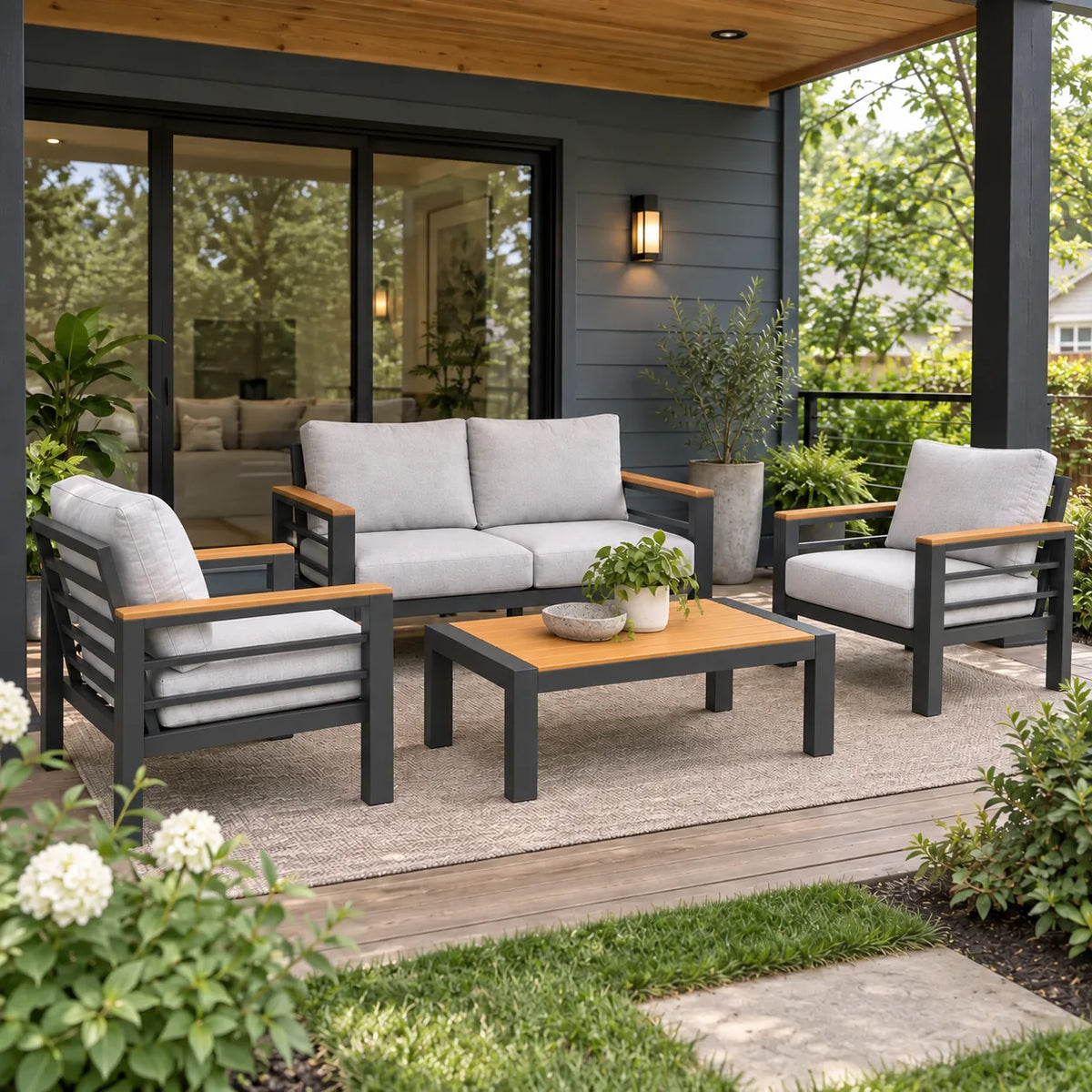 Four-piece outdoor patio loveseat set with two armchairs and a coffee table on a covered porch