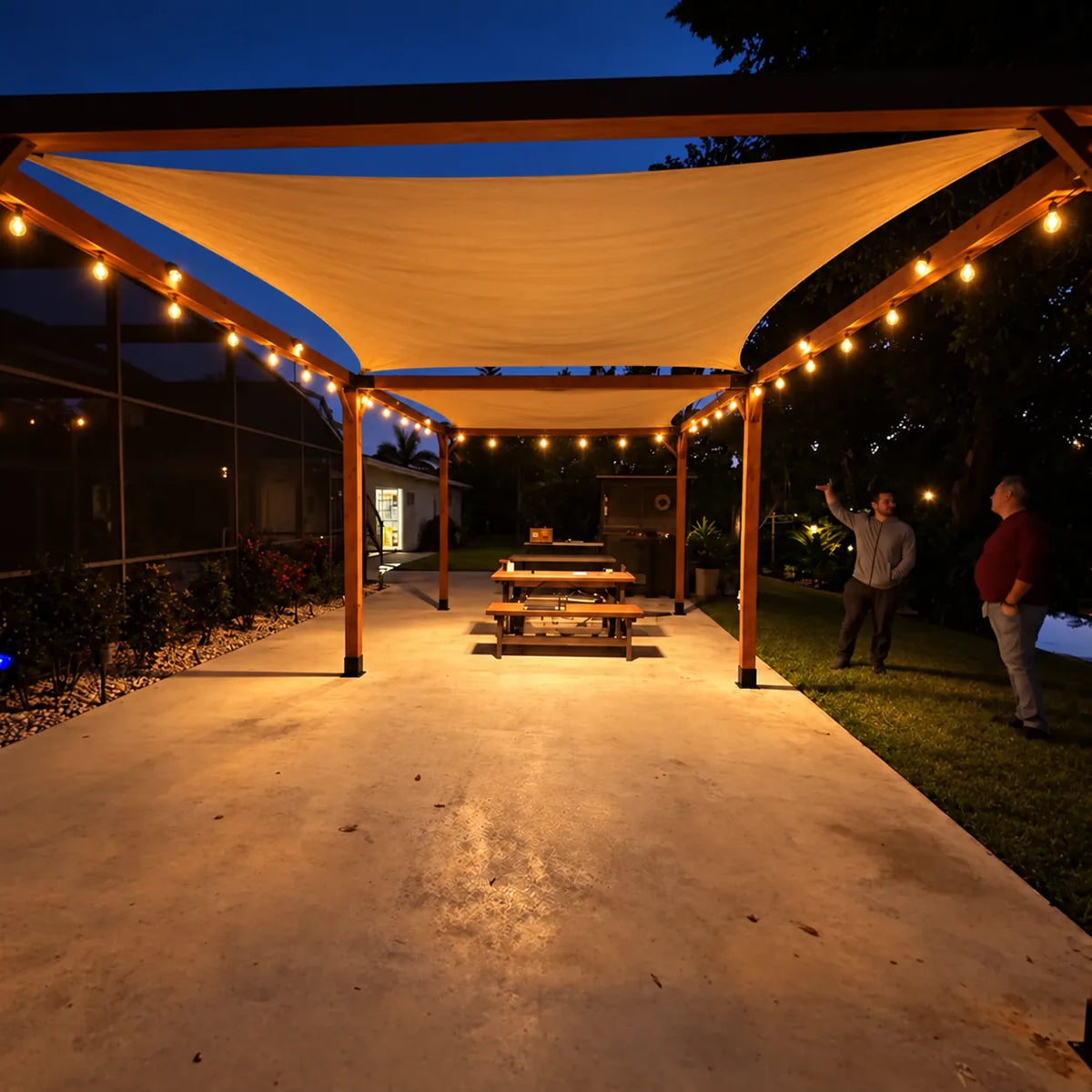 Wood pergola with naturally draped shade sails and warm string lights at night